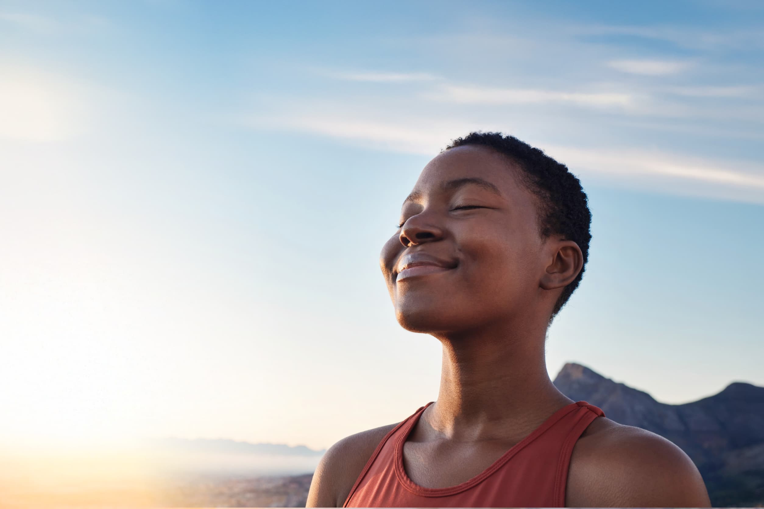Person smiling with closed eyes, facing the sun