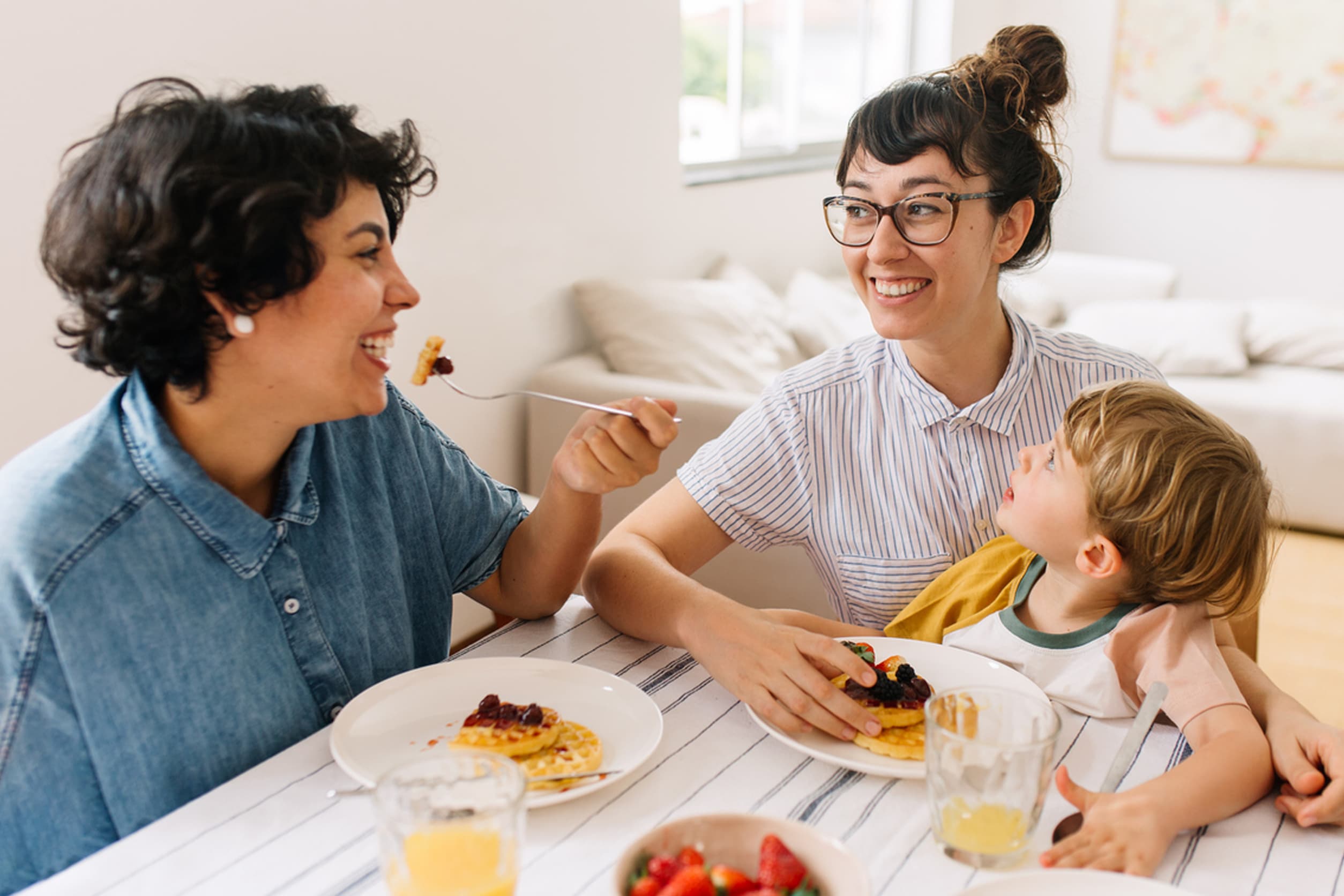 Happy couple with their child gathered around a table and eating