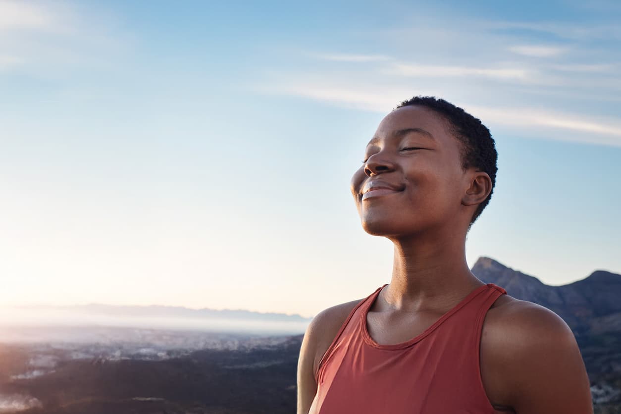 Person smiling with closed eyes, facing the sun