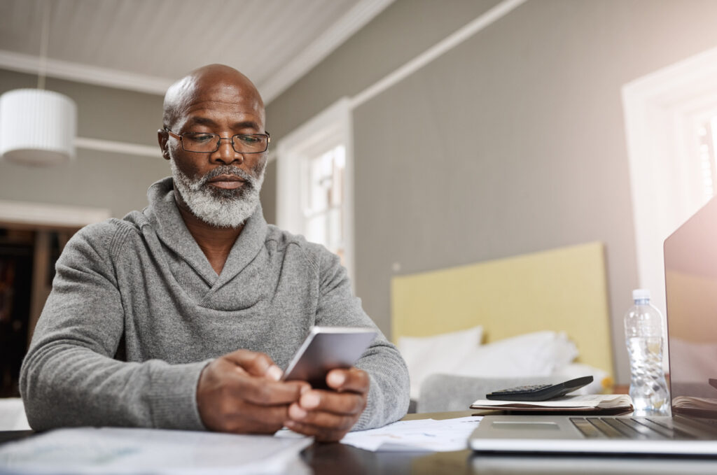 Older gentleman sitting at his table and scrolling through his phone