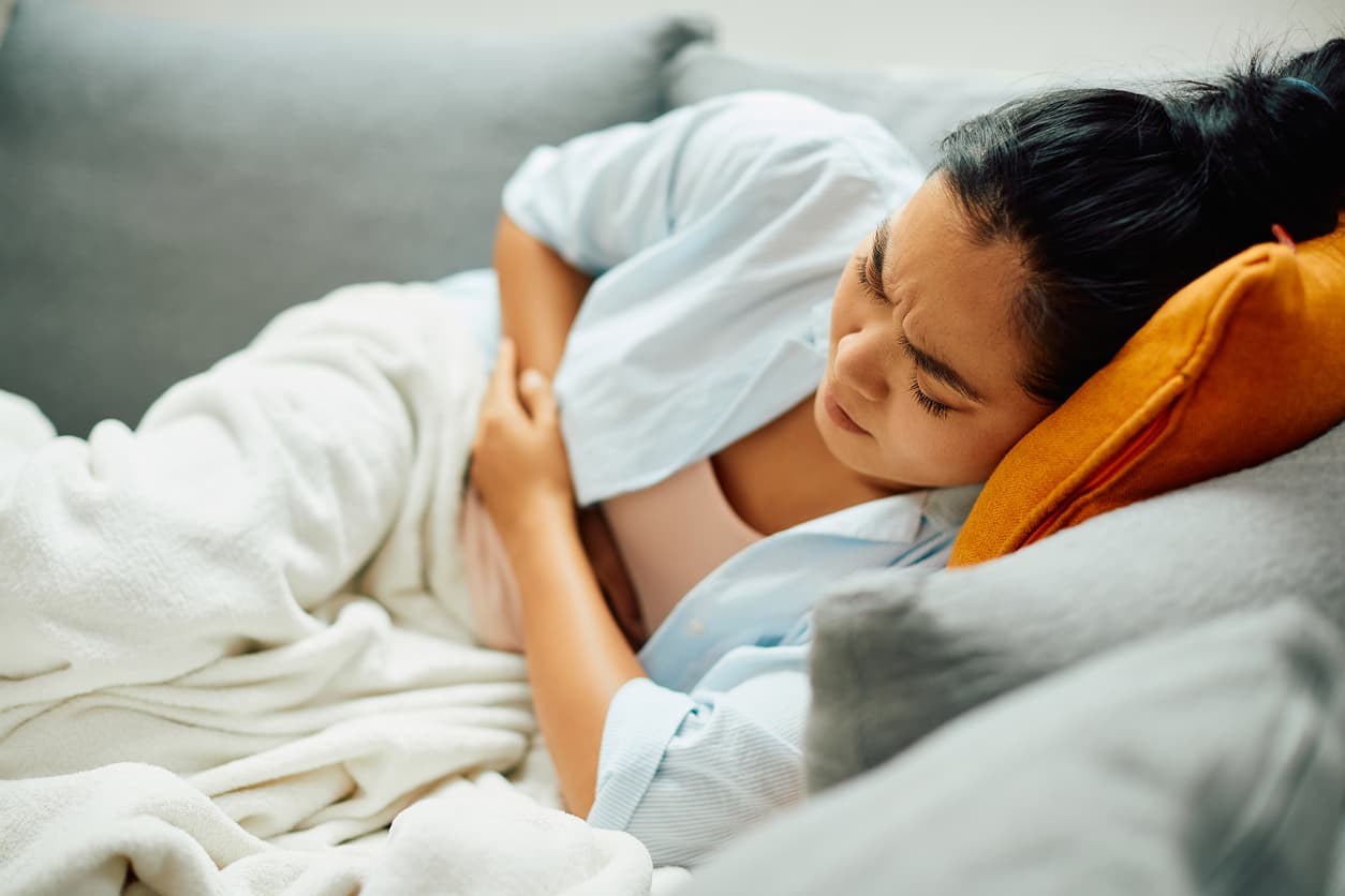 Woman laying on the sofa clutching her abdomen