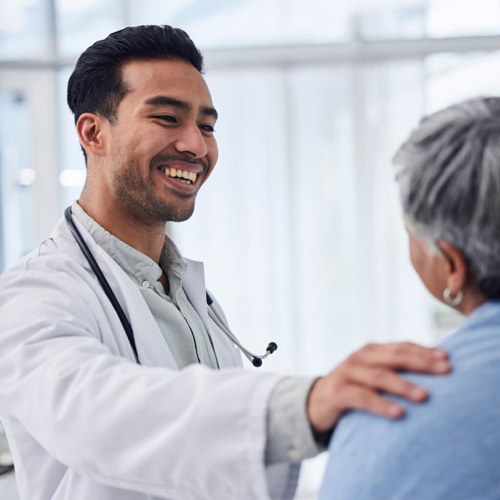 Friendly doctor putting his hand on patient's shoulder and smiling