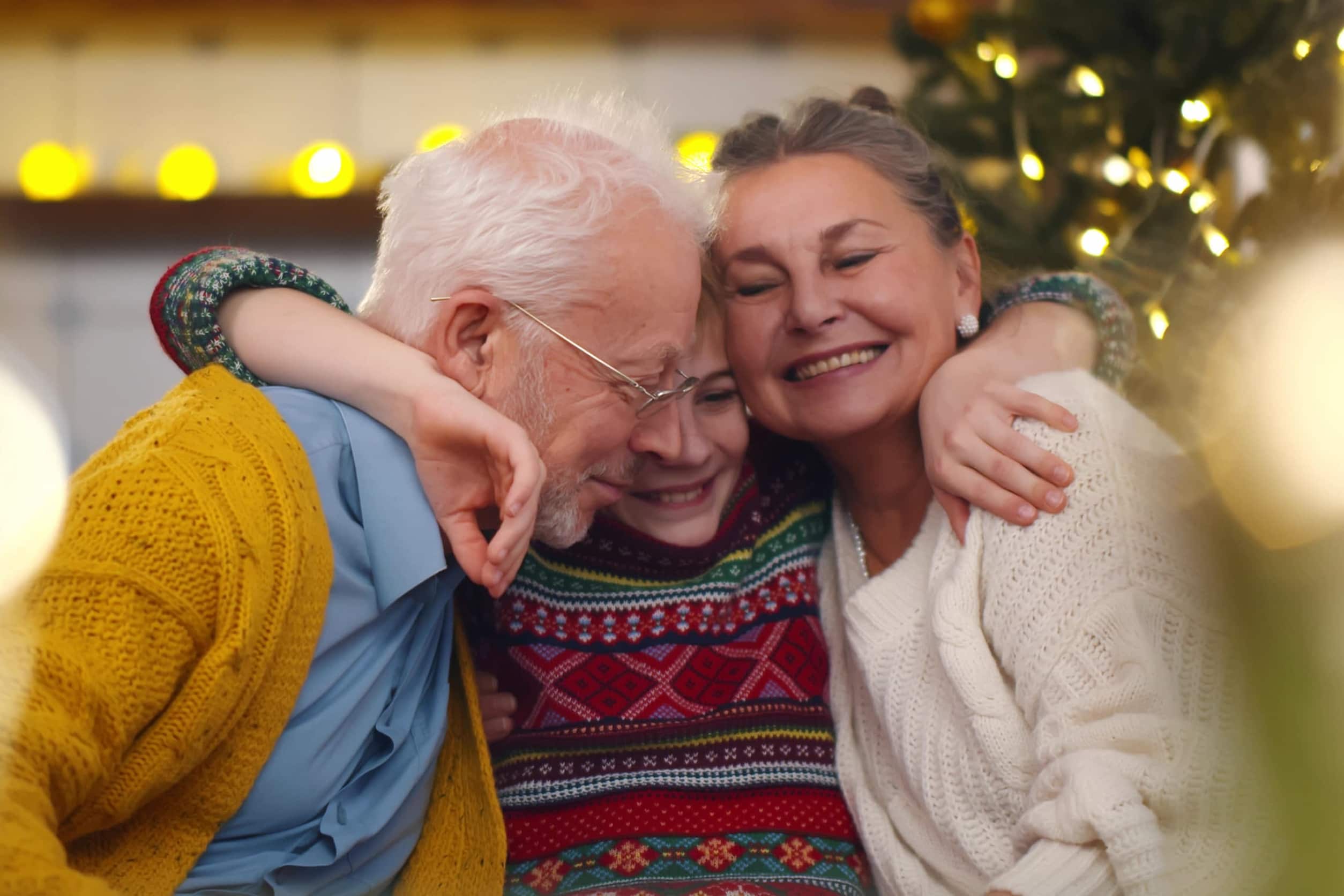 Smiling grandparents and grandson sitting on couch at home